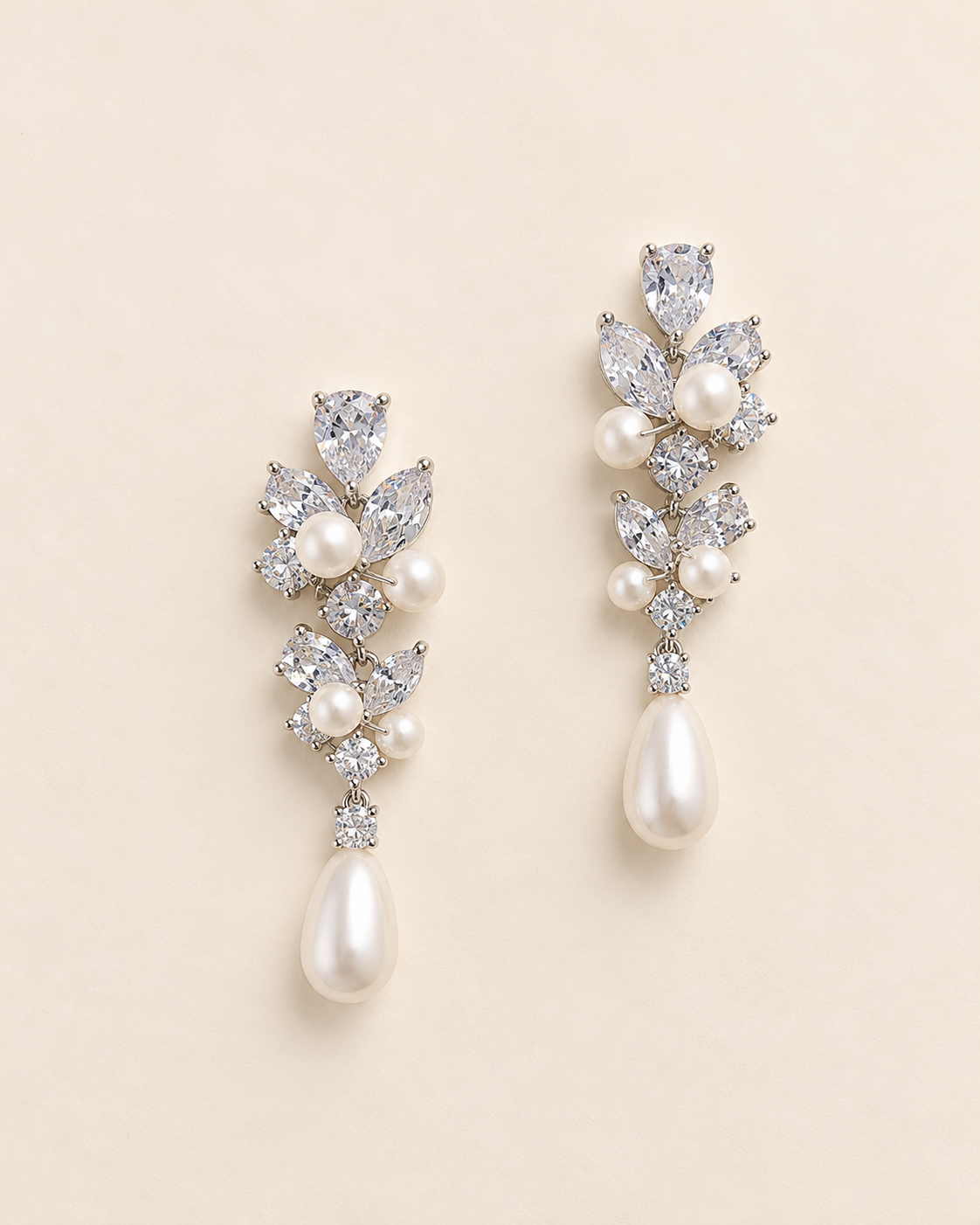 Abigail silver-finish floral drop earrings with clear faceted accents and ivory pearl-look teardrops on a cream background