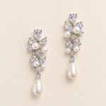 Abigail silver-finish floral drop earrings with clear faceted accents and ivory pearl-look teardrops on a cream background
