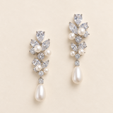 Abigail silver-finish floral drop earrings with clear faceted accents and ivory pearl-look teardrops on a cream background