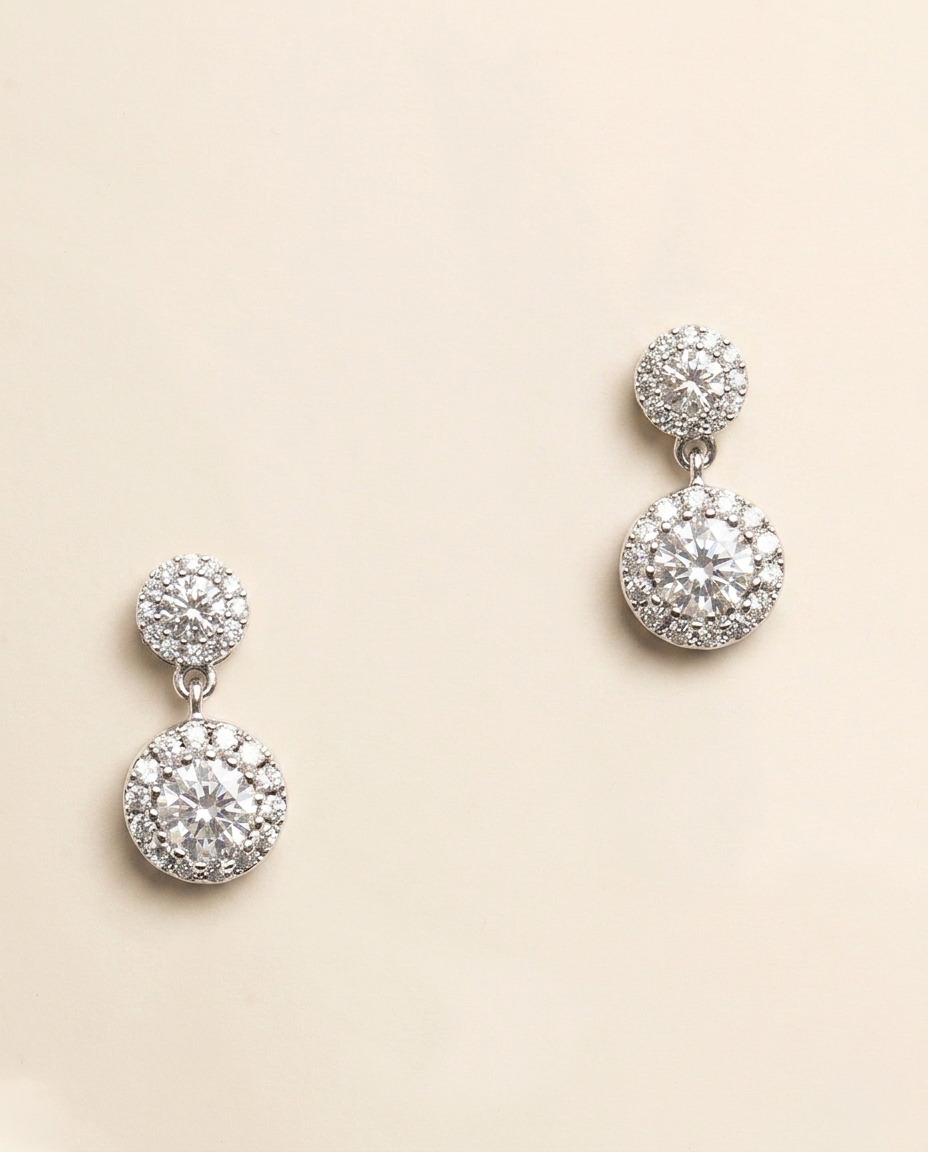 A pair of elegant diamond earrings with a large central stone surrounded by smaller stones, set in a silver or white metal frame.