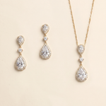 A set of three gold-colored jewelry pieces, including earrings and a necklace, featuring large, clear gemstones.