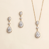 A set of three gold-colored jewelry pieces, including earrings and a necklace, featuring large, clear gemstones.