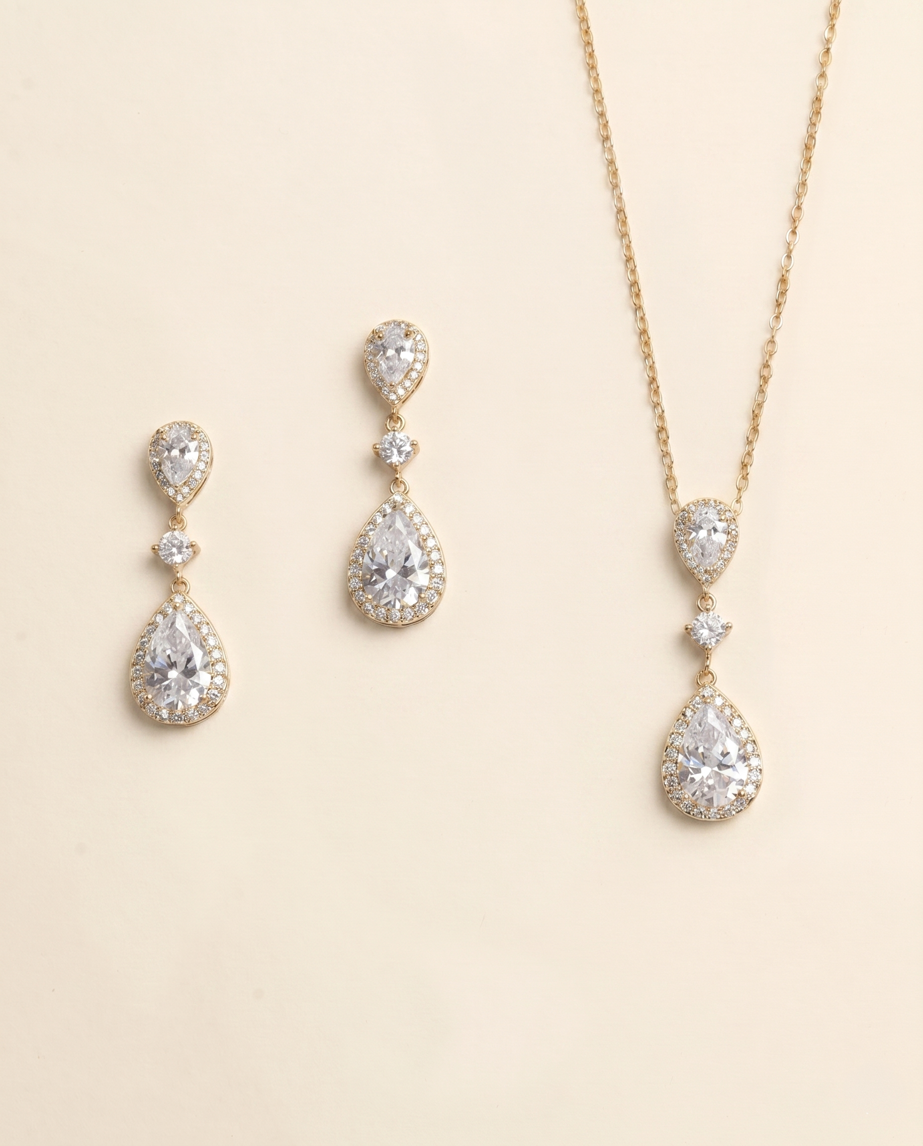 A set of three gold-colored jewelry pieces, including earrings and a necklace, featuring large, clear gemstones.