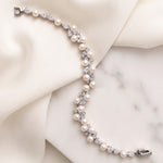 Athena silver-finish bracelet laid across cream fabric and a pale stone surface