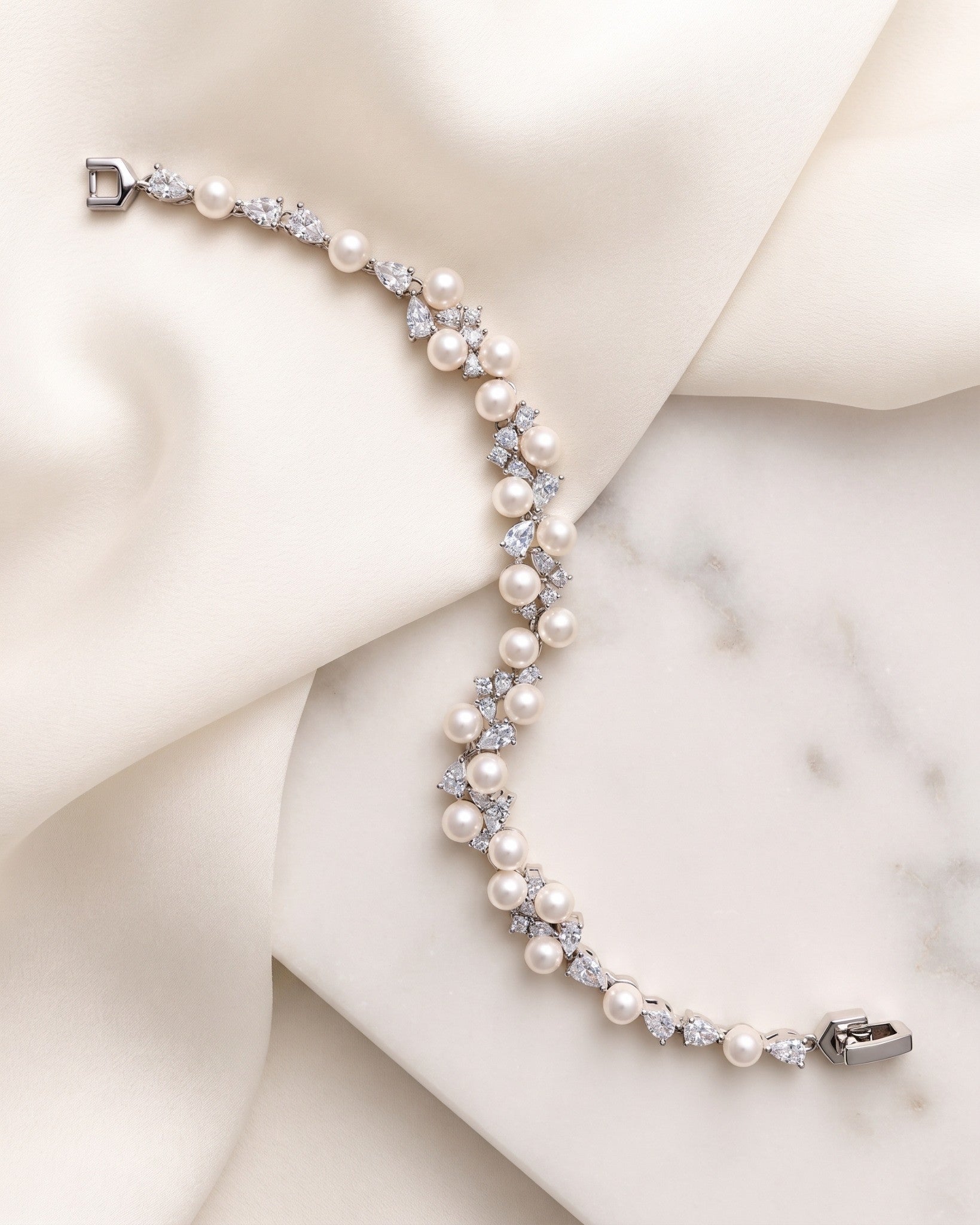 Athena silver-finish bracelet laid across cream fabric and a pale stone surface