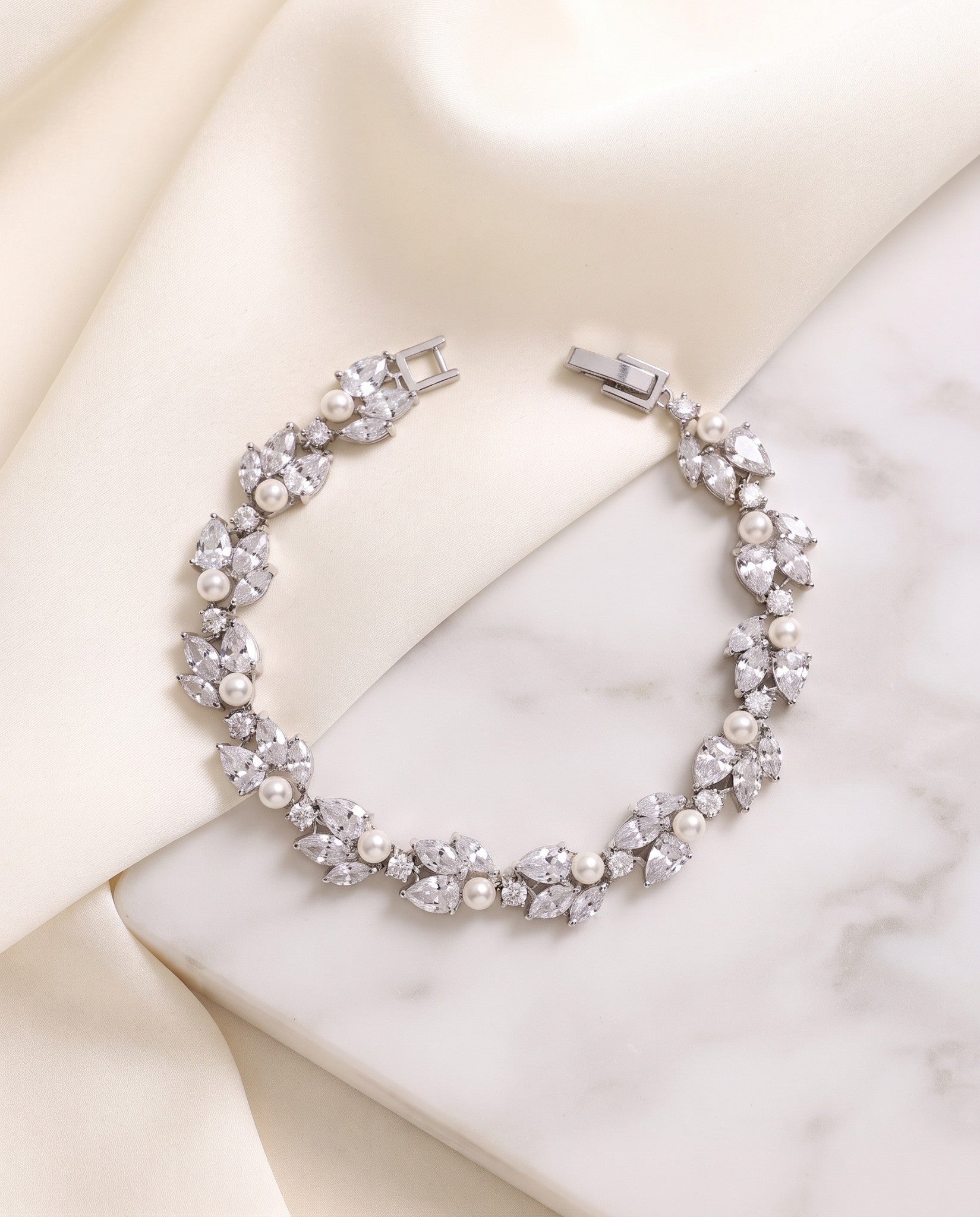 Audrey silver pearl and cubic zirconia bracelet arranged on satin and a marble surface