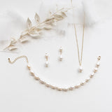 A collection of elegant pearl jewelry, including a necklace, earrings, and a bracelet, arranged on a white background.
