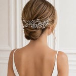 the back view of a woman's hair, with a decorative hair accessory, possibly a hairpiece or veil, pinned to her hair.