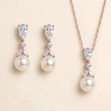 A necklace and earrings set featuring a pendant and a pearl.
