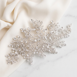 a delicate, sparkling crystal piece, possibly a brooch or headband, resting on a white marble surface.