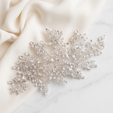 a delicate, sparkling crystal piece, possibly a brooch or headband, resting on a white marble surface.