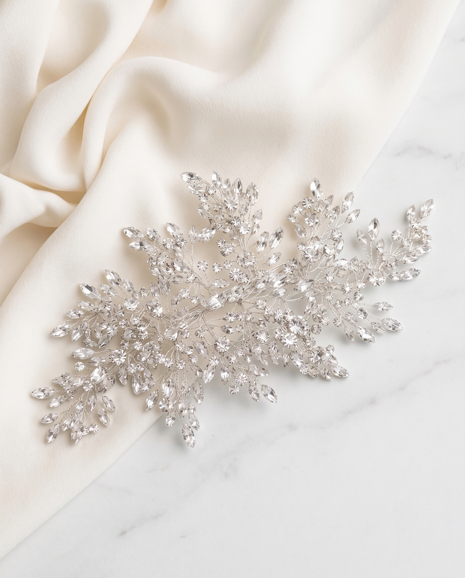 a delicate, sparkling crystal piece, possibly a brooch or headband, resting on a white marble surface.
