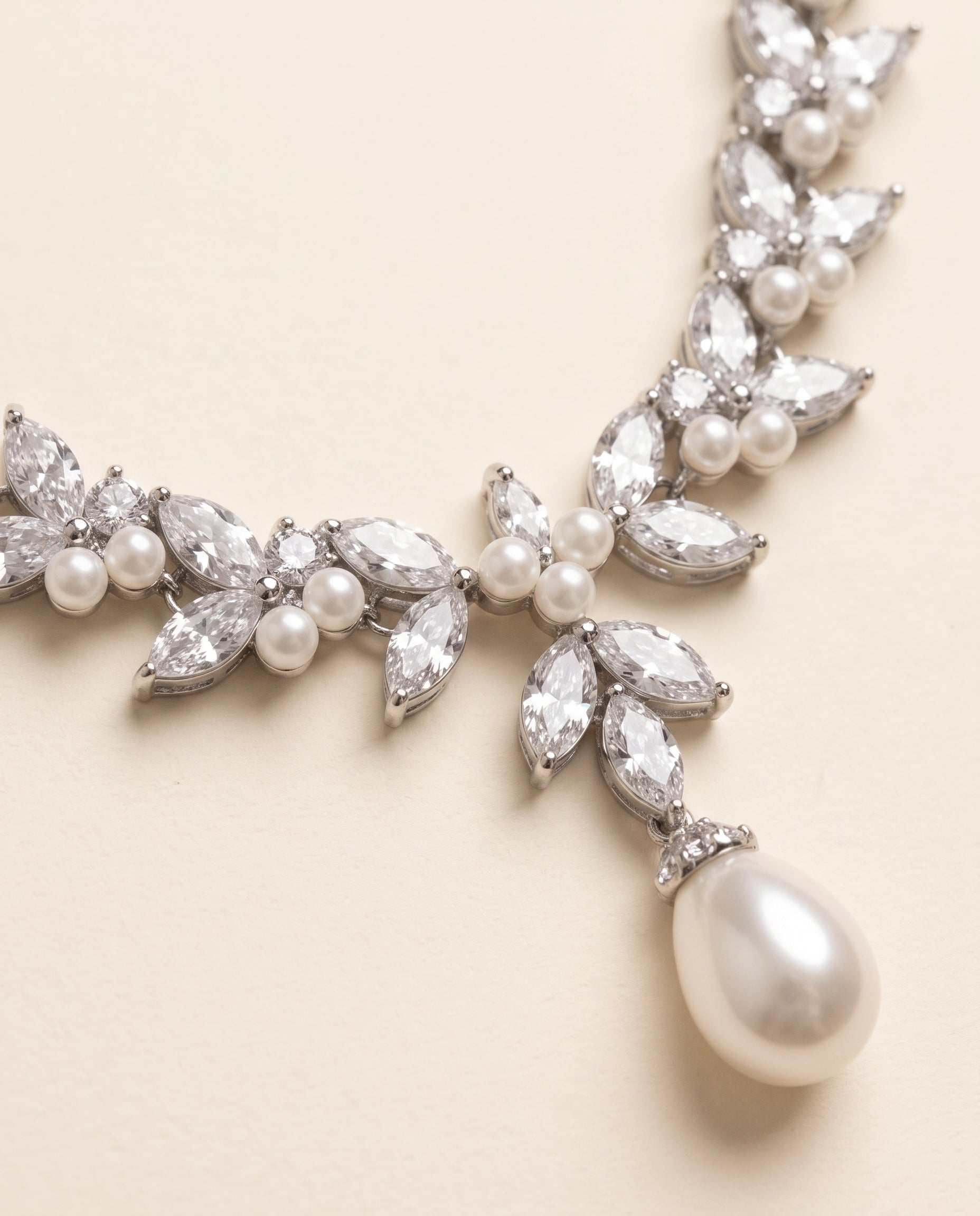 A close-up view of a delicate necklace with a large pearl pendant and a cluster of sparkling crystal stones.