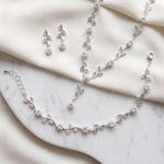 A delicate necklace, bracelet, and earrings are arranged on a white marble surface, creating an elegant and sophisticated display.