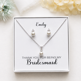 A necklace and earrings set presented in a white box, with a personalized message on the box.