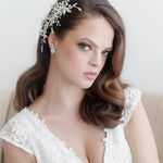 A woman with long brown hair wearing a white lace dress and a decorative headpiece, looking directly at the camera with a serious expression.