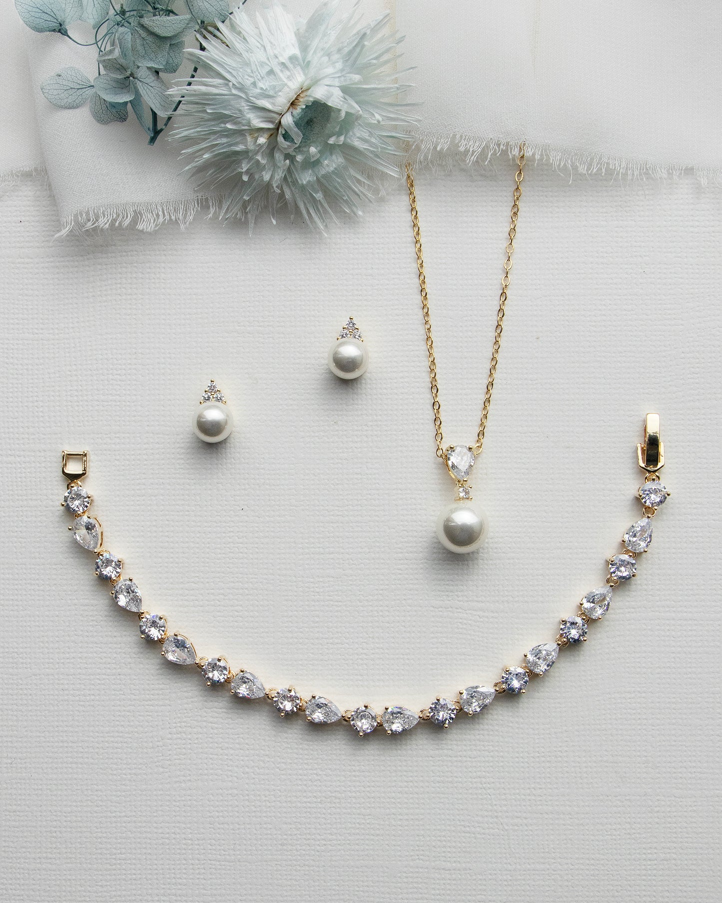a necklace, earrings, and bracelet on a white surface