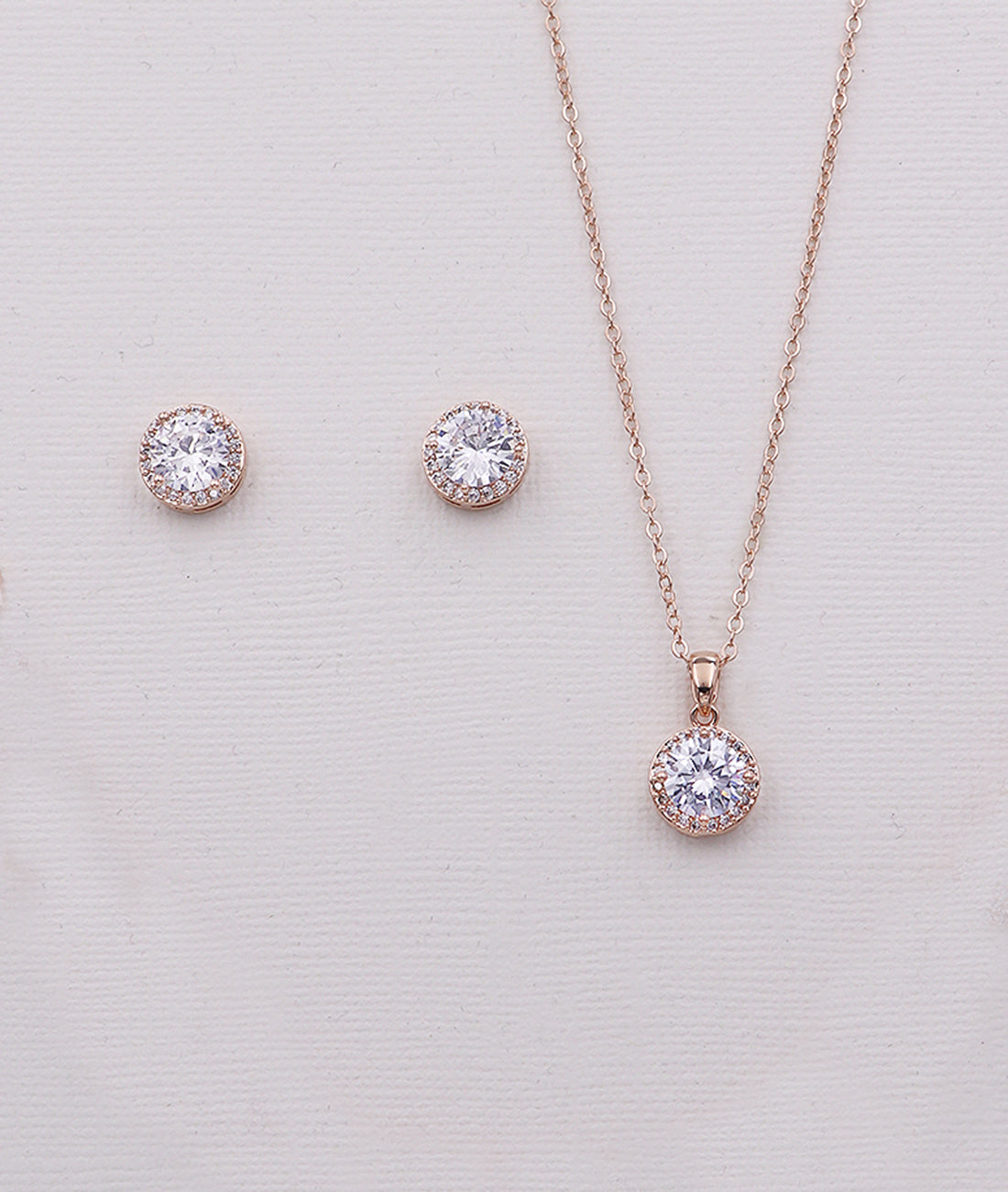 a delicate gold necklace and earrings set with a large, sparkling crystal pendant.