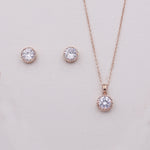 a delicate gold necklace and earrings set with a large, sparkling crystal pendant.