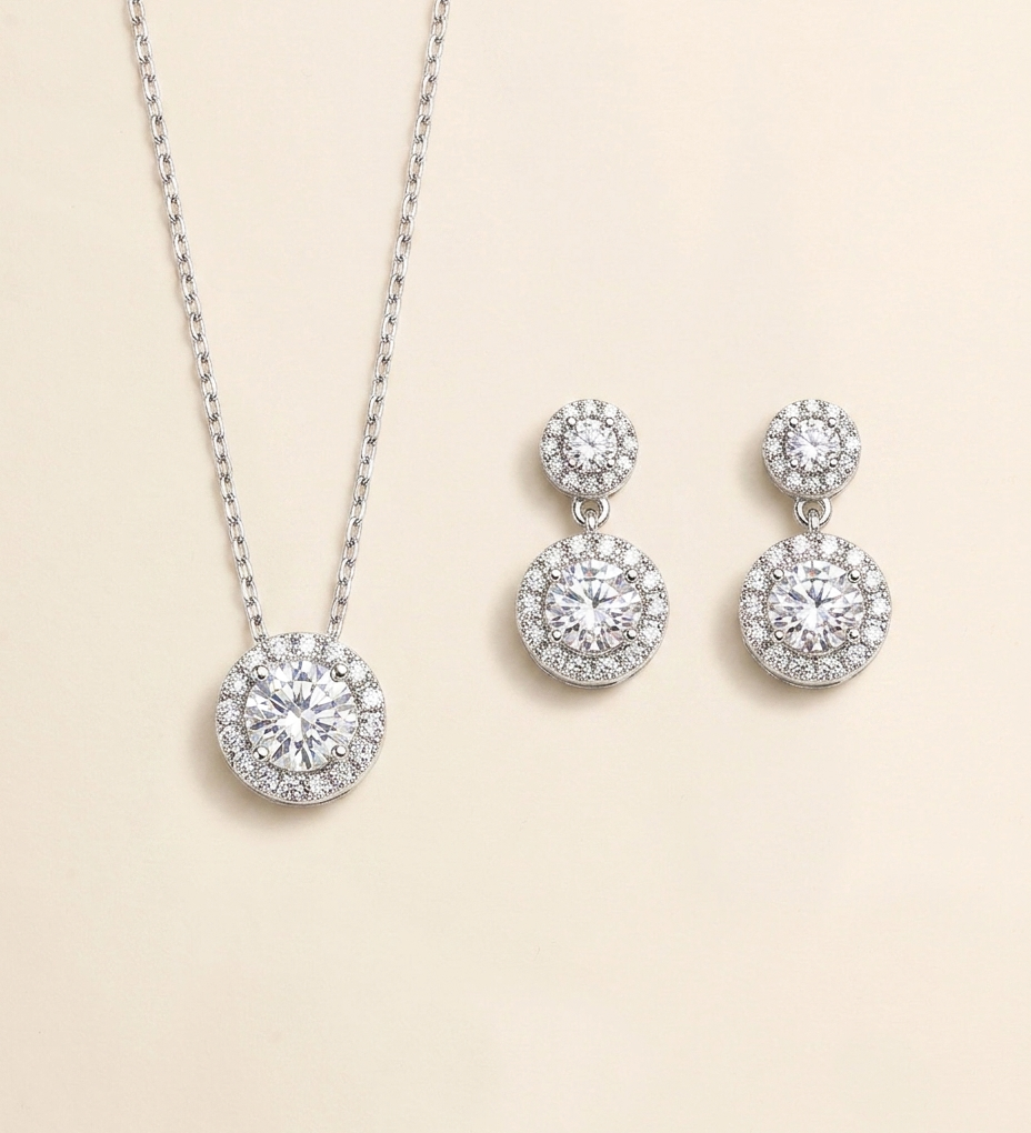 A necklace with a pendant and a pair of earrings with a central stone are displayed against a light beige background.
