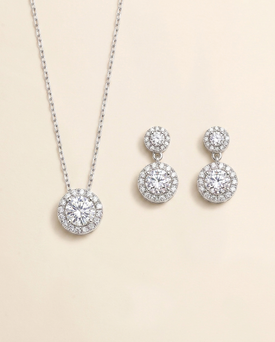 A necklace with a pendant and a pair of earrings with a central stone are displayed against a light beige background.