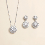 A necklace with a pendant and a pair of earrings with a central stone are displayed against a light beige background.