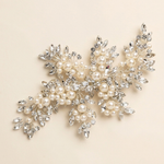 A decorative piece of jewelry with a combination of pearls, crystals, and leaves.