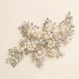 A decorative piece of jewelry with a combination of pearls, crystals, and leaves.