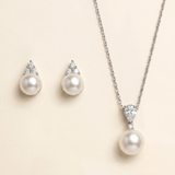 A necklace with a pendant and earrings made of pearls and diamonds.