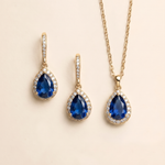 A gold necklace and earrings set with blue gemstones.