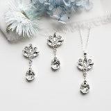 a necklace, earrings, and flower on a white surface