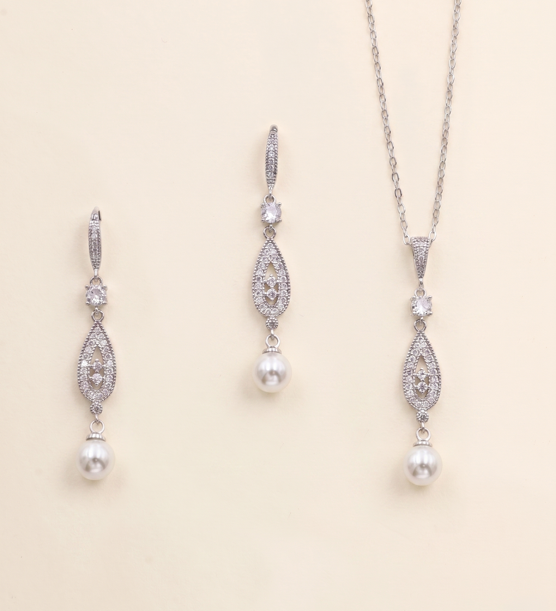 A necklace and earrings set made of silver and white pearls, with dangling crystal pendants.