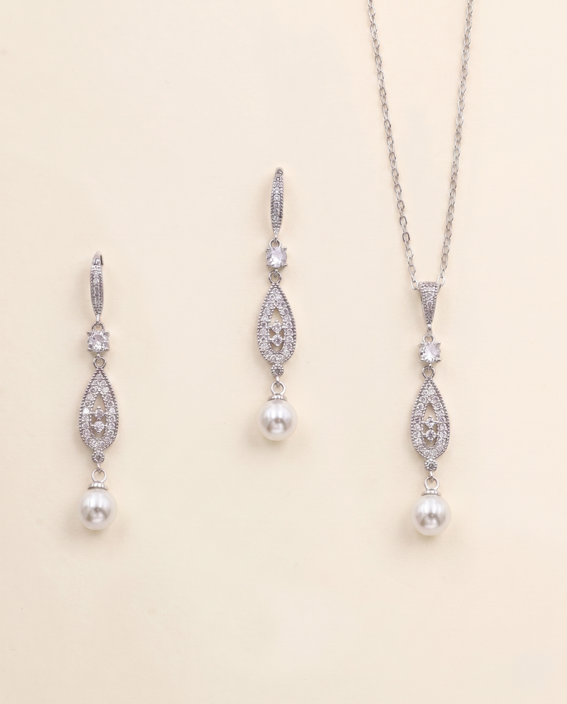 A necklace and earrings set made of silver and white pearls, with dangling crystal pendants.
