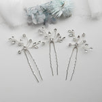 three silver hair pins with flowers on them