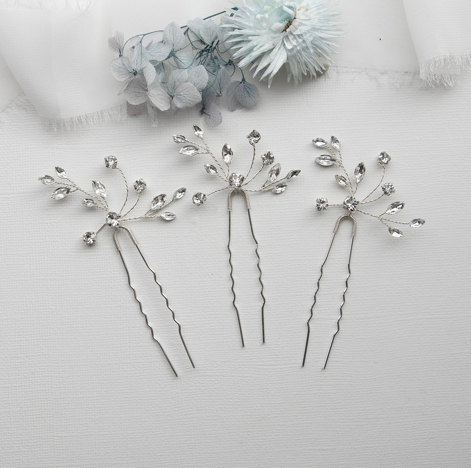 three silver hair pins with flowers on them