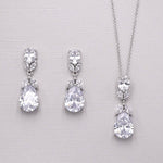 A pair of elegant earrings and a necklace with large, sparkling diamonds are displayed against a light background.