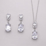 A pair of elegant earrings and a necklace with large, sparkling diamonds are displayed against a light background.