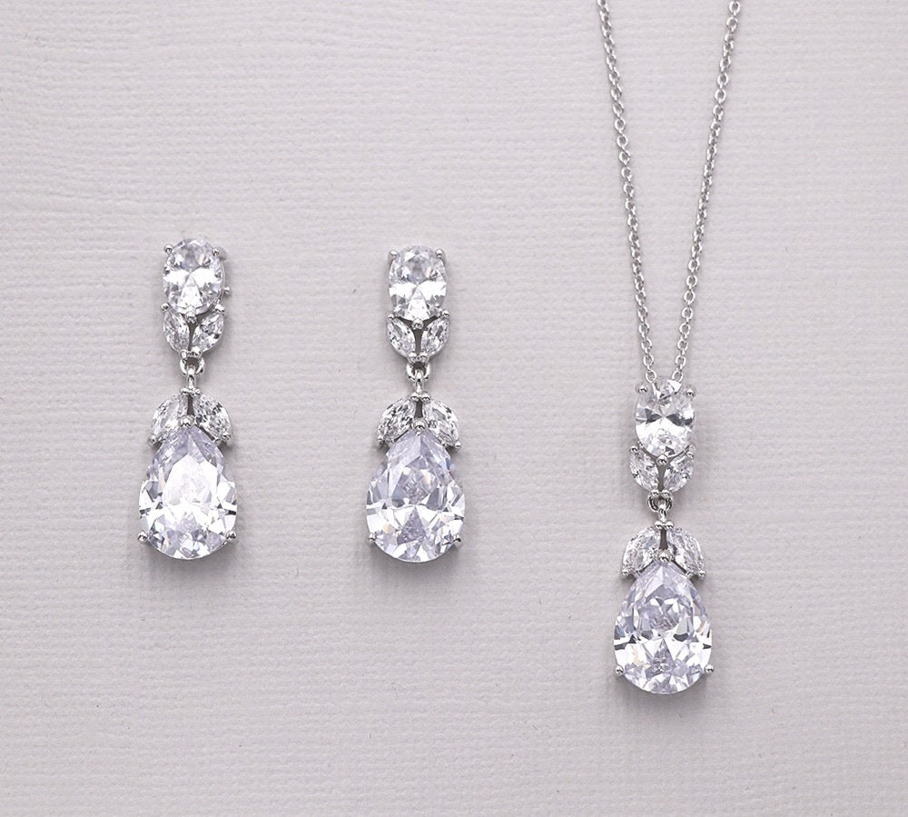 A pair of elegant earrings and a necklace with large, sparkling diamonds are displayed against a light background.