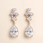 A pair of elegant gold earrings with large, clear gemstones hanging from the bottom.