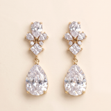 A pair of elegant gold earrings with large, clear gemstones hanging from the bottom.