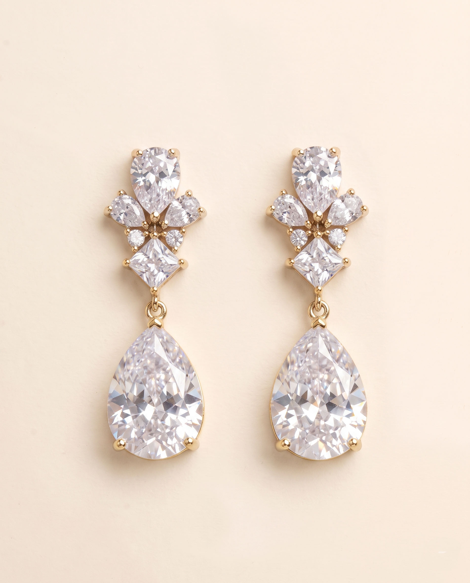 A pair of elegant gold earrings with large, clear gemstones hanging from the bottom.