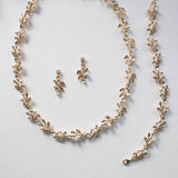A delicate gold necklace with leaf-shaped pendants and a matching earring set, all adorned with small pearls and crystals.