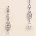 A pair of elegant earrings with pearls and diamonds, featuring a delicate and intricate design.