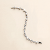A bracelet made of white pearls and diamonds is shown against a light beige background.