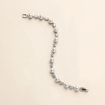 A bracelet made of white pearls and diamonds is shown against a light beige background.