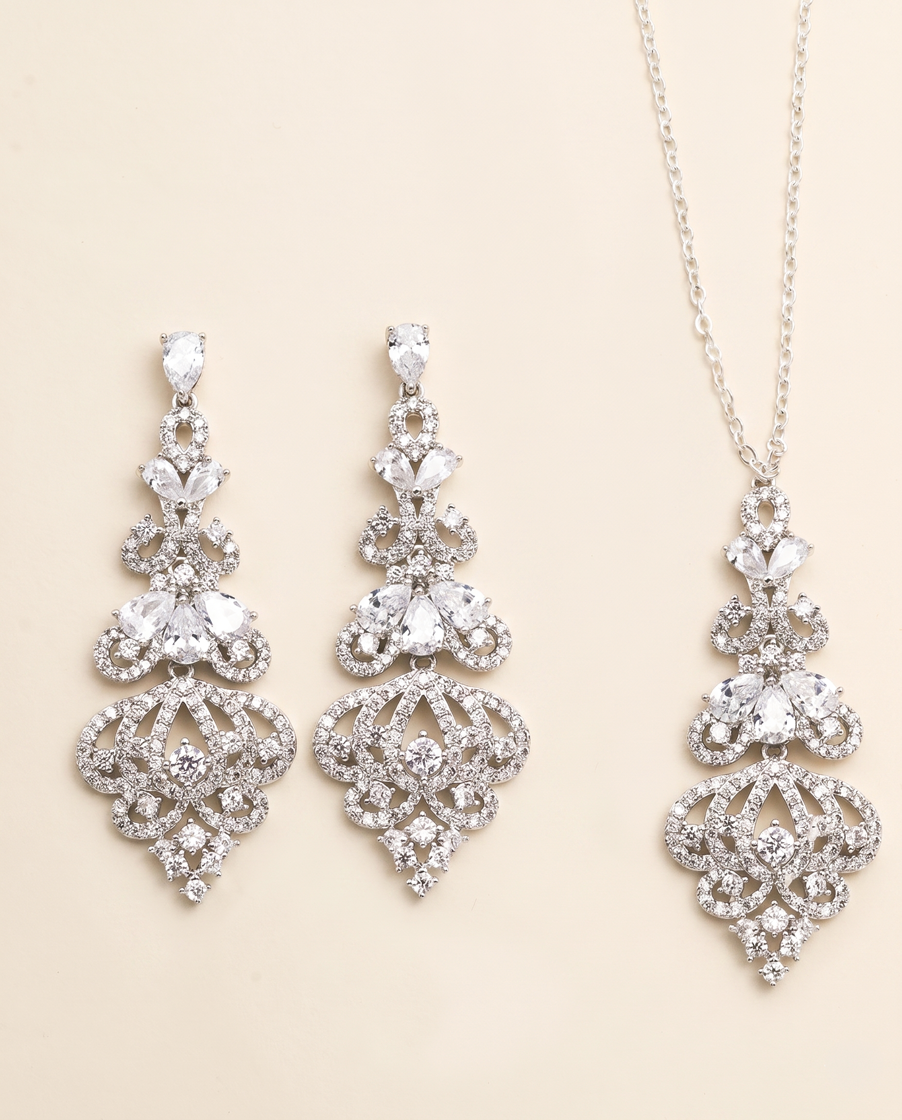 a set of elegant jewelry pieces, including earrings and a necklace, both adorned with intricate designs and sparkling crystal elements.