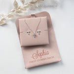 A necklace with two cross pendants and a matching cross pendant set in a tan-colored box, labeled "Sophia First Communion"