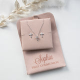 A necklace with two cross pendants and a matching cross pendant set in a tan-colored box, labeled "Sophia First Communion"