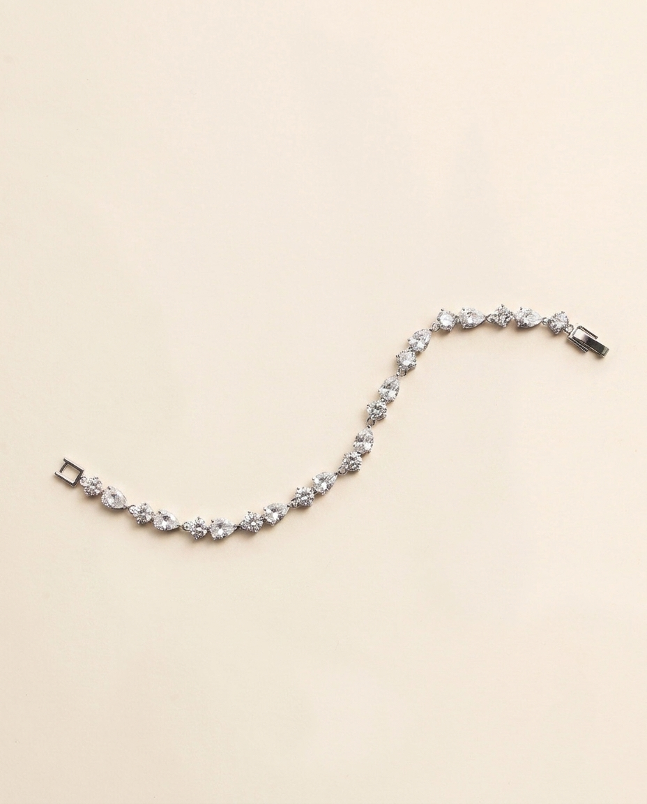 A delicate bracelet adorned with numerous small, clear gemstones is displayed against a light beige background.
