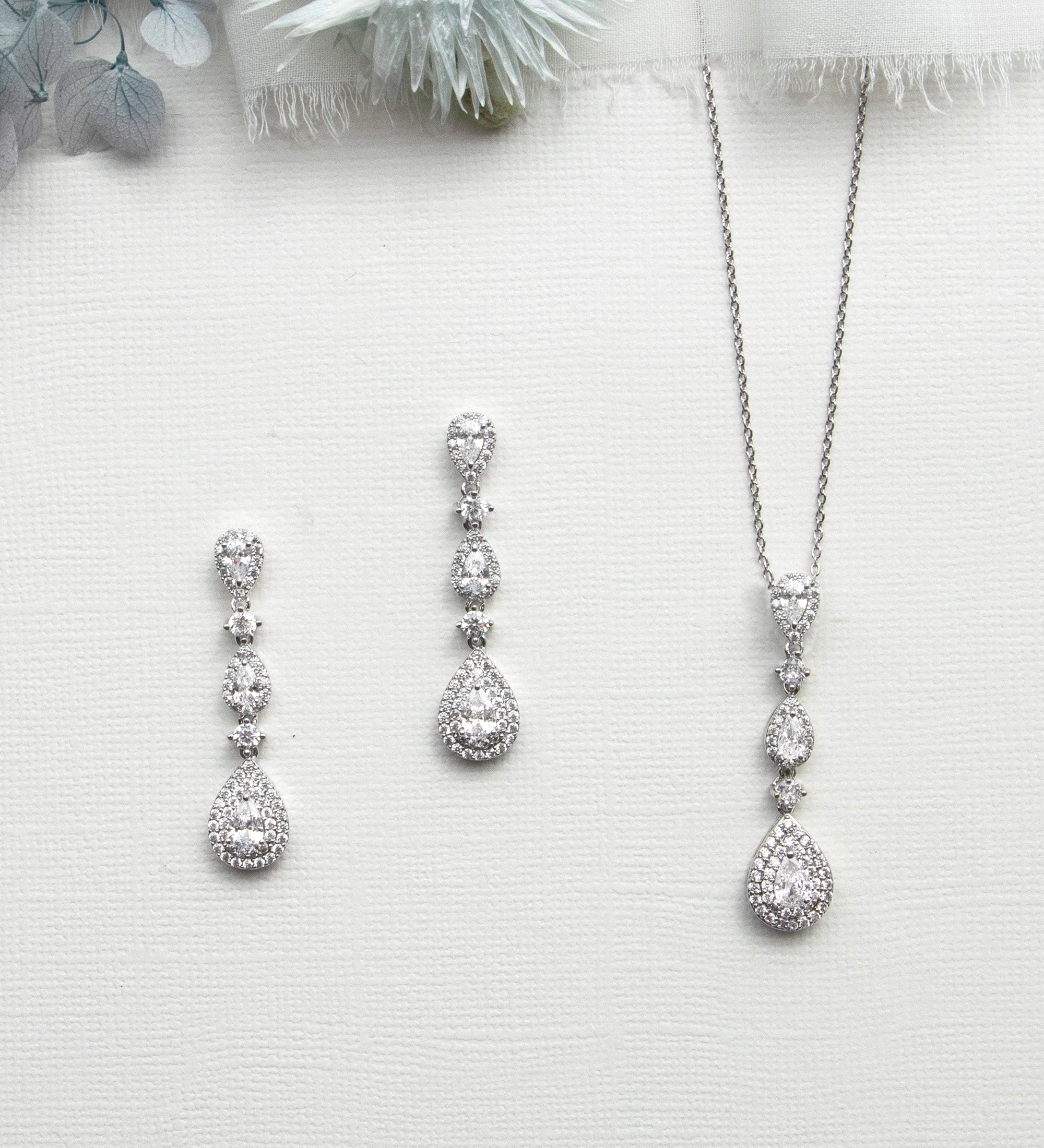a collection of elegant jewelry pieces, including a necklace, earrings, and a pendant, all featuring a sparkling diamond design.